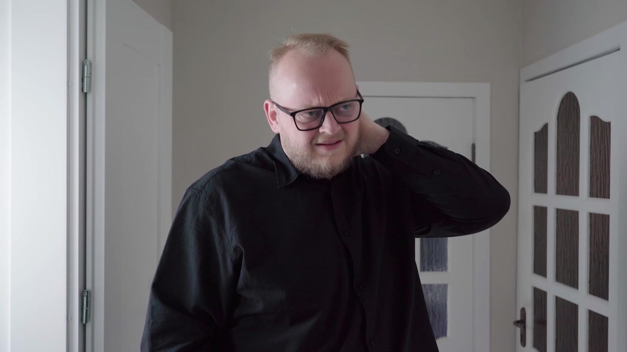 Adult man looks down at his smartphone then clutches the back of his neck in discomfort from tech overuse.