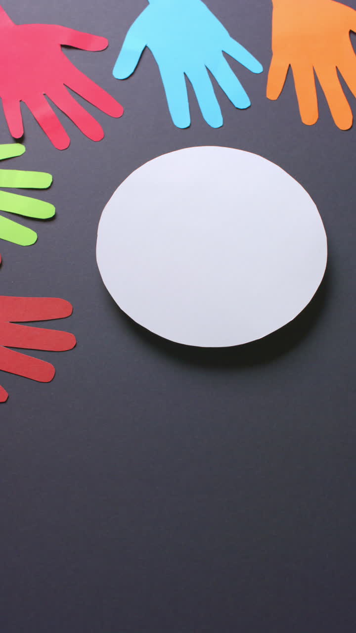 Vertical video of hands around circle made of colourful paper on gray background with copy space
