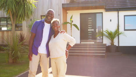 Portrait-Of-Senior-Couple-Standing-In-Driveway-In-Front-Of-Dream-Home-Together