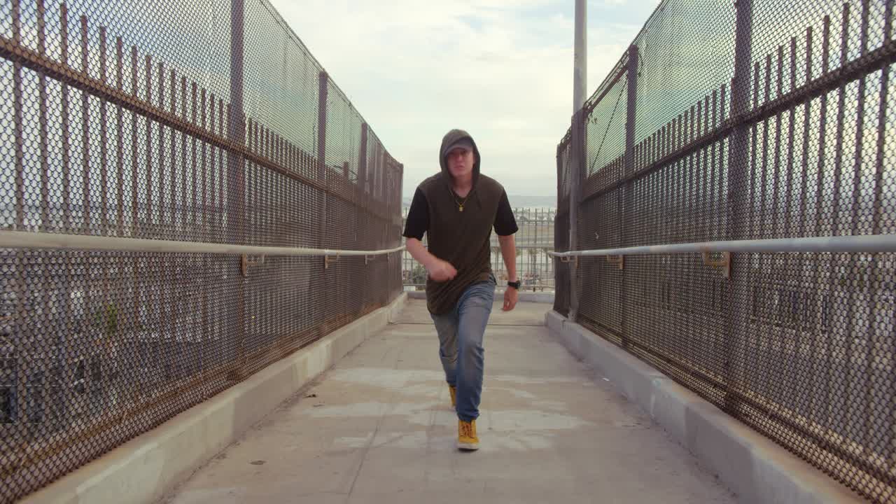 Man freestyle hip hop dancing across freeway overpass in city