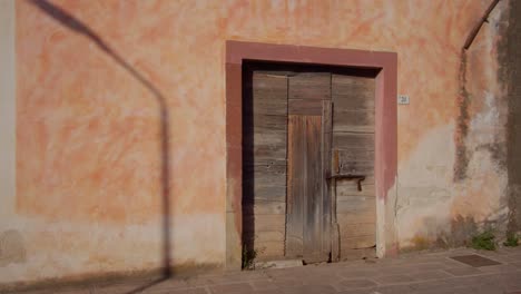 Antiguas-Puertas-Históricas-De-Madera-En-La-Pared-Del-Edificio-En-La-Calle-De-Cerdeña,-Vista-En-Movimiento