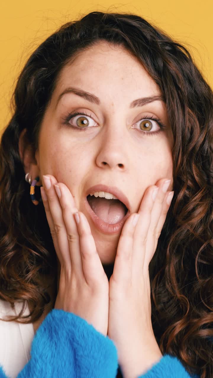 Giovane Donna che Esprime Sorpresa e Felicità su Sfondo Giallo