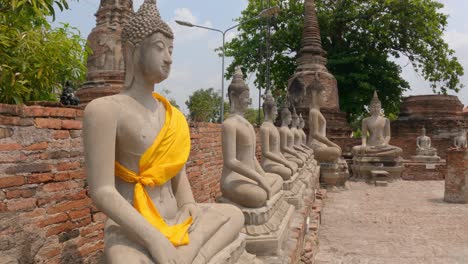 row of buddha statues at wat yai chai mongkhon, buddhist temple in ayutthaya, thailand. - wide shot