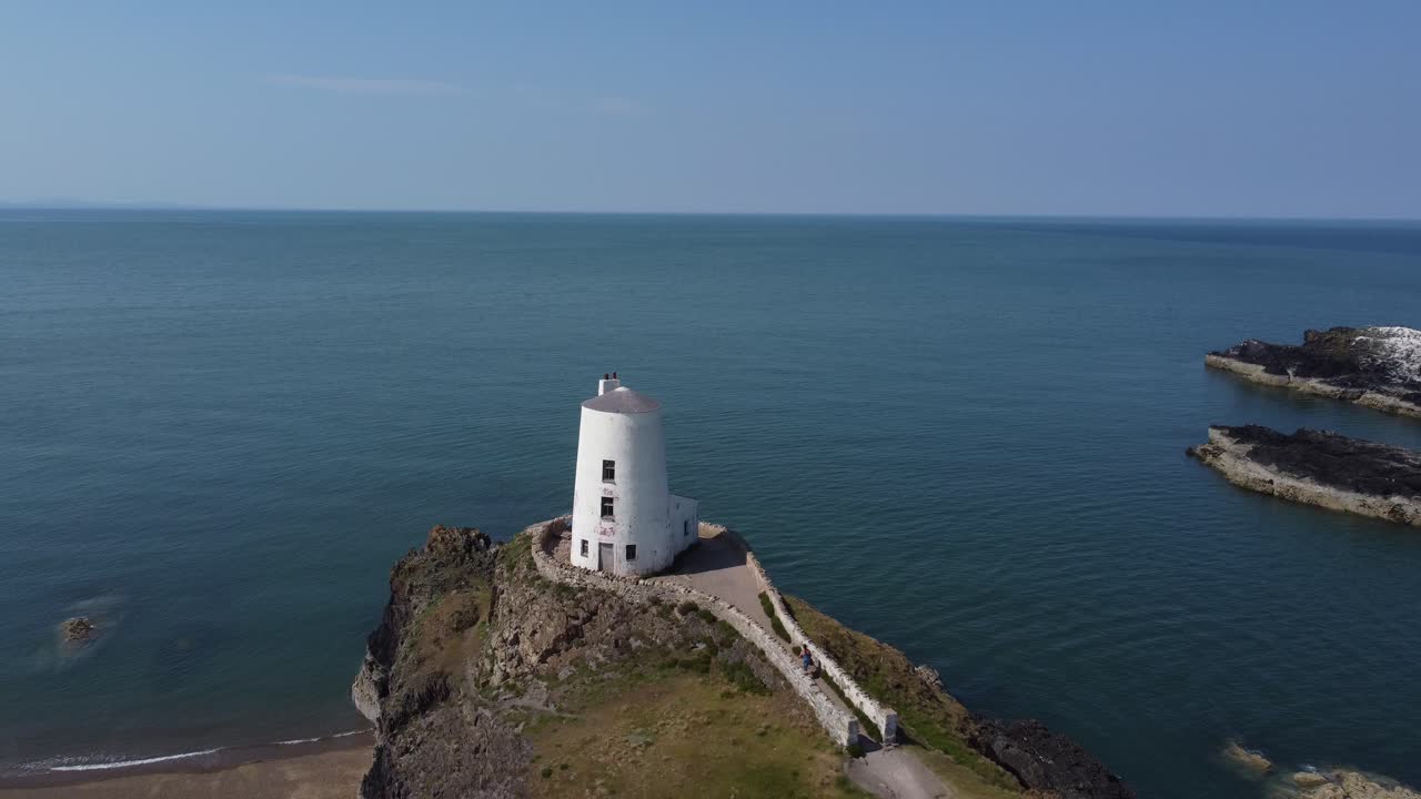 estableciendo una vista aérea en el sendero costero de llanddwyn hacia el faro de piedra goleudy tŵr mawr y las montañas de snowdonia, anglesey