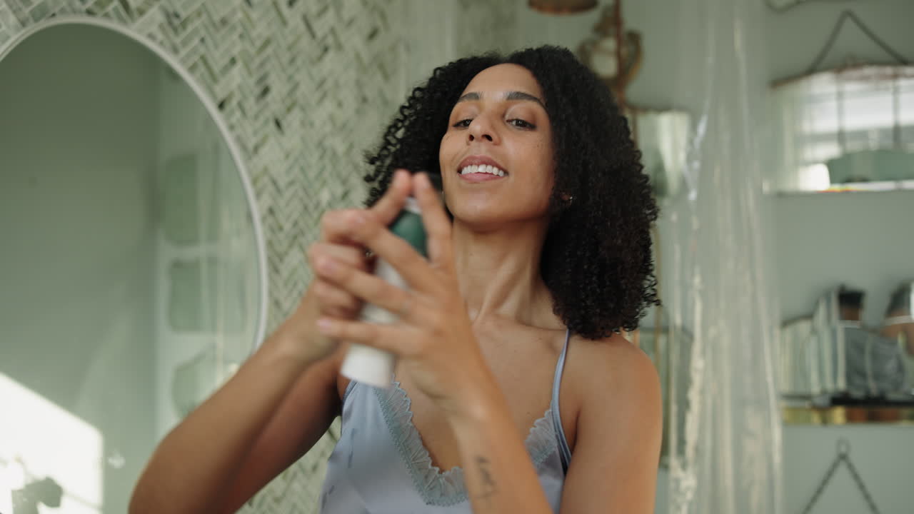 Young Woman Applying Deodorant Spray in Bathroom