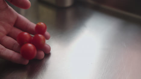 a hand placing cherry tomatoes on a metal surface