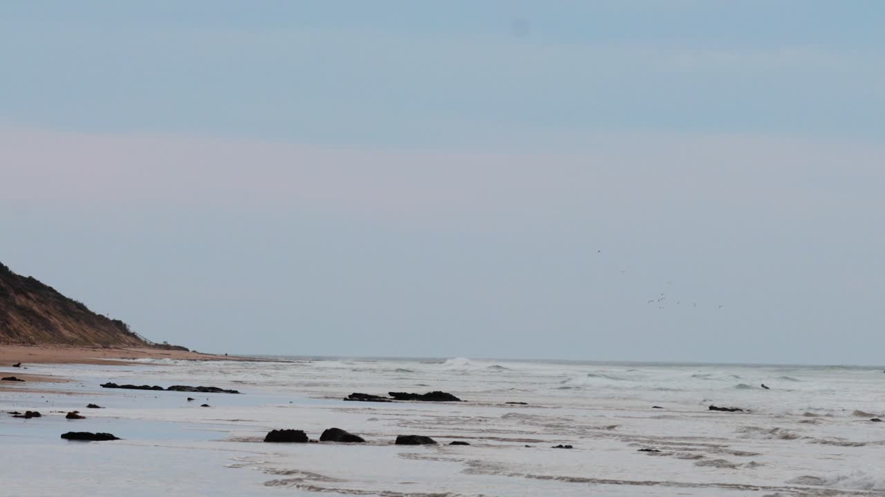 부드러운 파도와 멀리 떨어진 절벽을 가진 조용한 해변 장면, 저녁에 오스트레일리아의 위대한 바다 도로를 따라 찍은