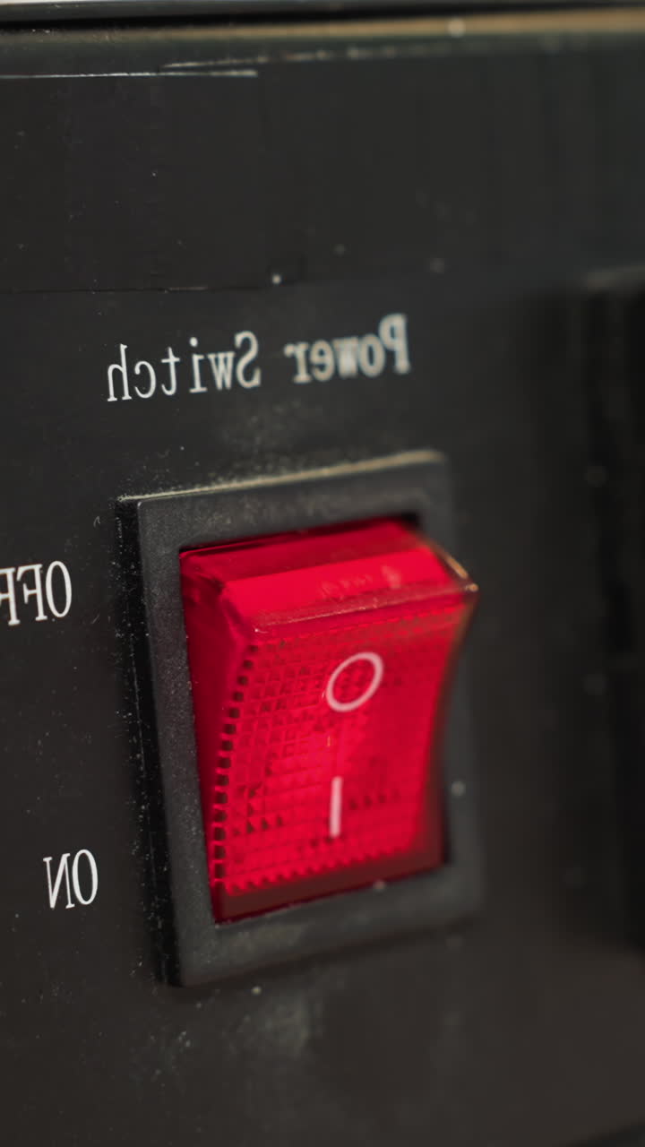 una vista de cerca de la mano con guantes de un técnico presionando el interruptor de energía rojo en un dispositivo de control de temperatura negra