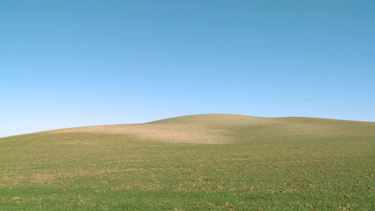 Smukke bølgende grønne marker og bakker antyder landbrug.