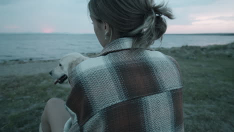 Happy-Woman-Petting-Cute-Dog-on-Lakeshore-in-Evening