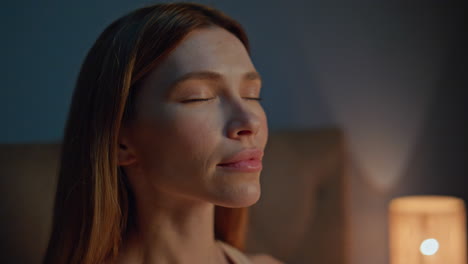 portrait girl meditating night apartment closing eyes. woman feeling tranquility