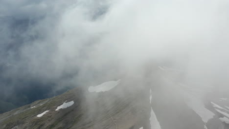 flying through clouds rolling over rocky mountain summit