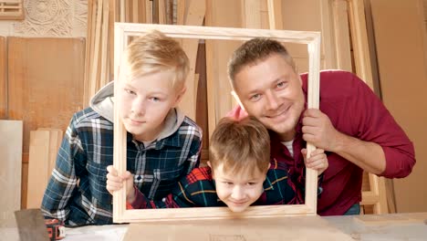 father is a carpenter's workshop son. friendly family indoors, funny portrait.