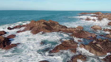 Toma-Aérea-De-Grandes-Olas-Rompiendo-En-Las-Rocas-En-Un-Día-Soleado,-Plemont-Bay,-Jersey,-Islas-Del-Canal,-4k