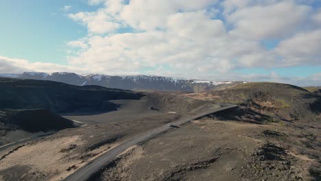 Witness-the-beauty-of-Icelandic-landscapes-seen-from-a-drone,-Follow-a-car-winding-through-volcanic-terrain,-conquering-rugged-landscapes-on-an-adventure