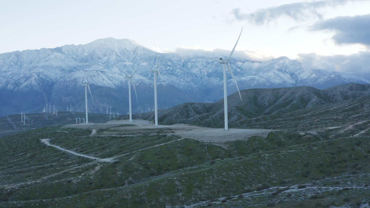 뒤에 눈 덮인 산이 있는 풍력 터빈의 공중 전망