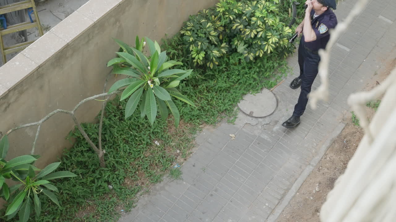 Guard or police officer patrols around building, Using his radio to communicate. Security, vigilance, and real-time coordination. Law enforcement, safety operations, surveillance, emergency response.