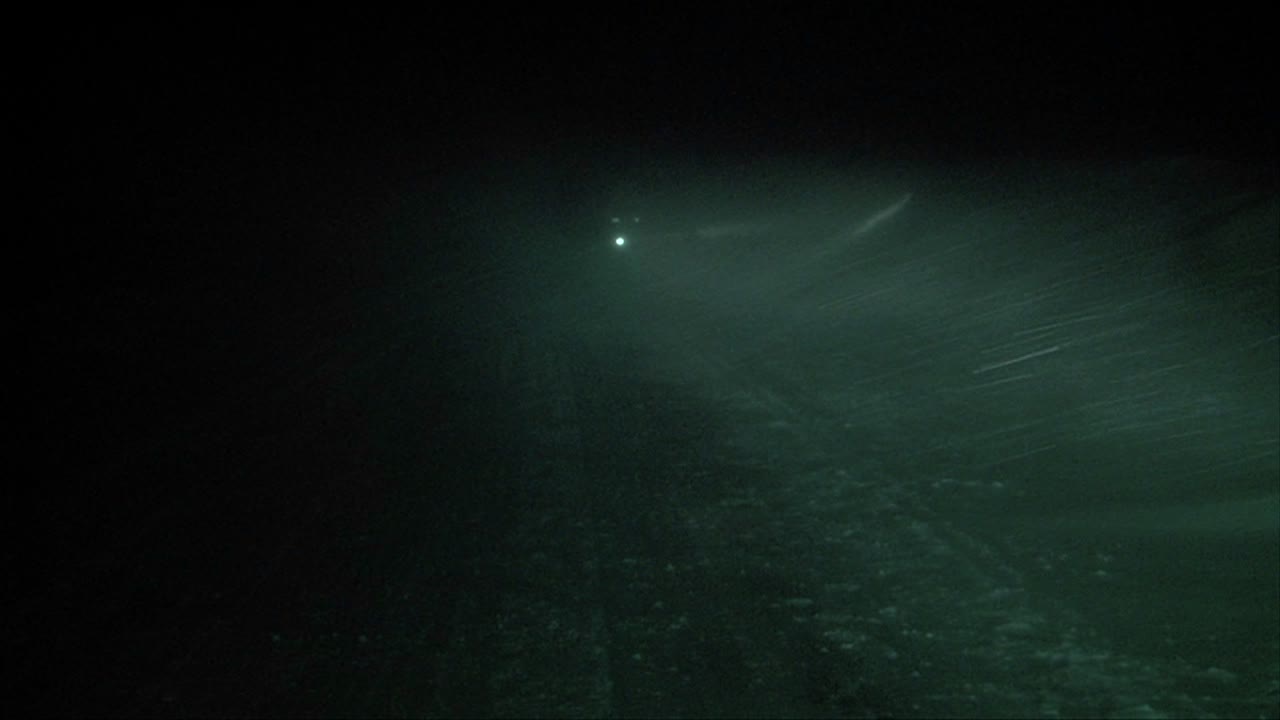 una persona con una linterna camina a través de una ventisca