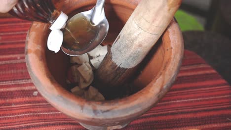 Cooking-Som-Tam-Series:-Slow-Motion,-Street-food-vendor-putting-fish-sauce-in-mortar-to-make-Som-Tam-or-Thai-spicy-green-papaya-salad,-one-of-Thailand's-most-popular-dishes