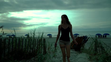 young woman walking in the sand on the oceanfront at sunset