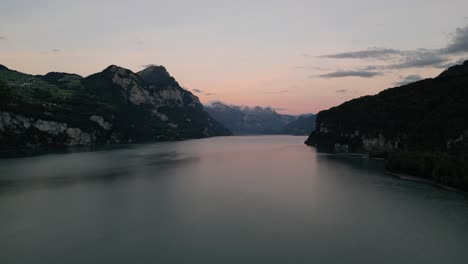 Drone-flight-forward-over-the-lake-between-mountains-with-beautiful-sky-near-Walensee-lake,-Switzerland-in-the-early-morning