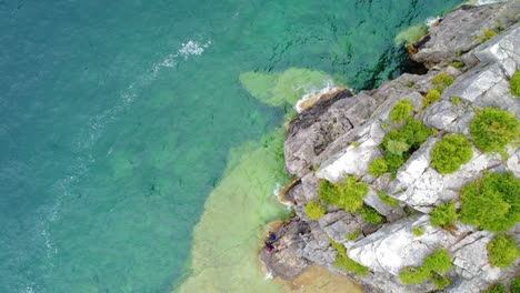 Von-Einer-Hohen,-Mit-Sträuchern-Bewachsenen-Klippe-Blicken-Sie-Auf-Das-Kristallklare-Wasser