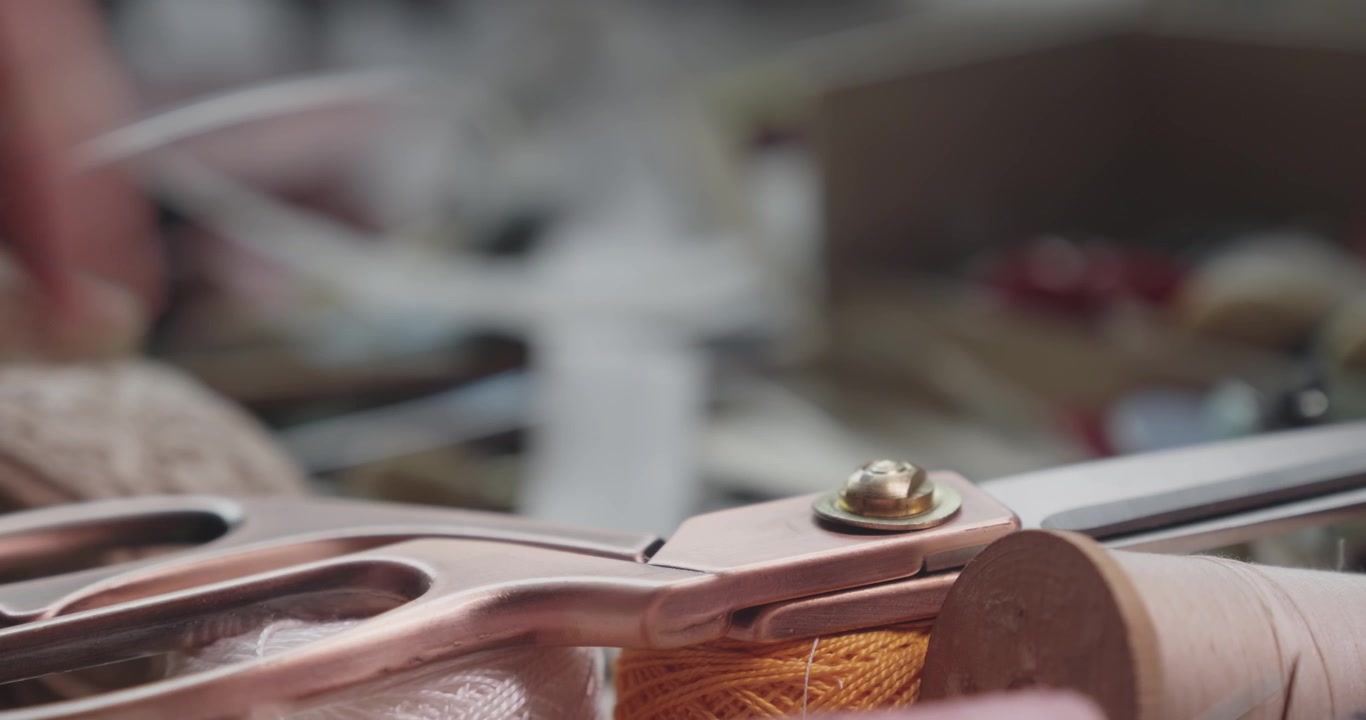 Close-up of tailoring scissors resting on cotton thread cones, highlighting garment production tools and traditional textile craftsmanship.