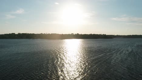 Aerial-wide-shot-of-sunlight-reflecting-off-a-pristine-lake