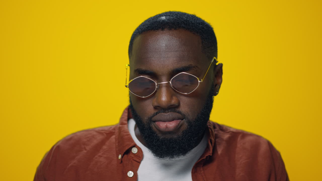 Portrait of smiling african american man dancing on yellow background.