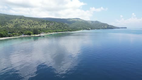 a calm tropical coastline with lush green hills and clear blue waters , aerial view