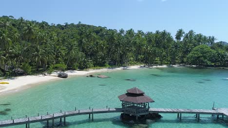 aerial, reverse, tilt down, drone shot of wooden pier, the turquoise sea and a paradise beach, on a sunny day, in koh kood, thailand, asia