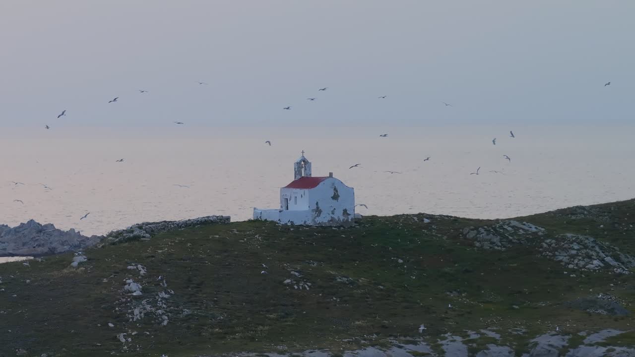 Seagulls flying in slow motion around small church in Greece at dusk