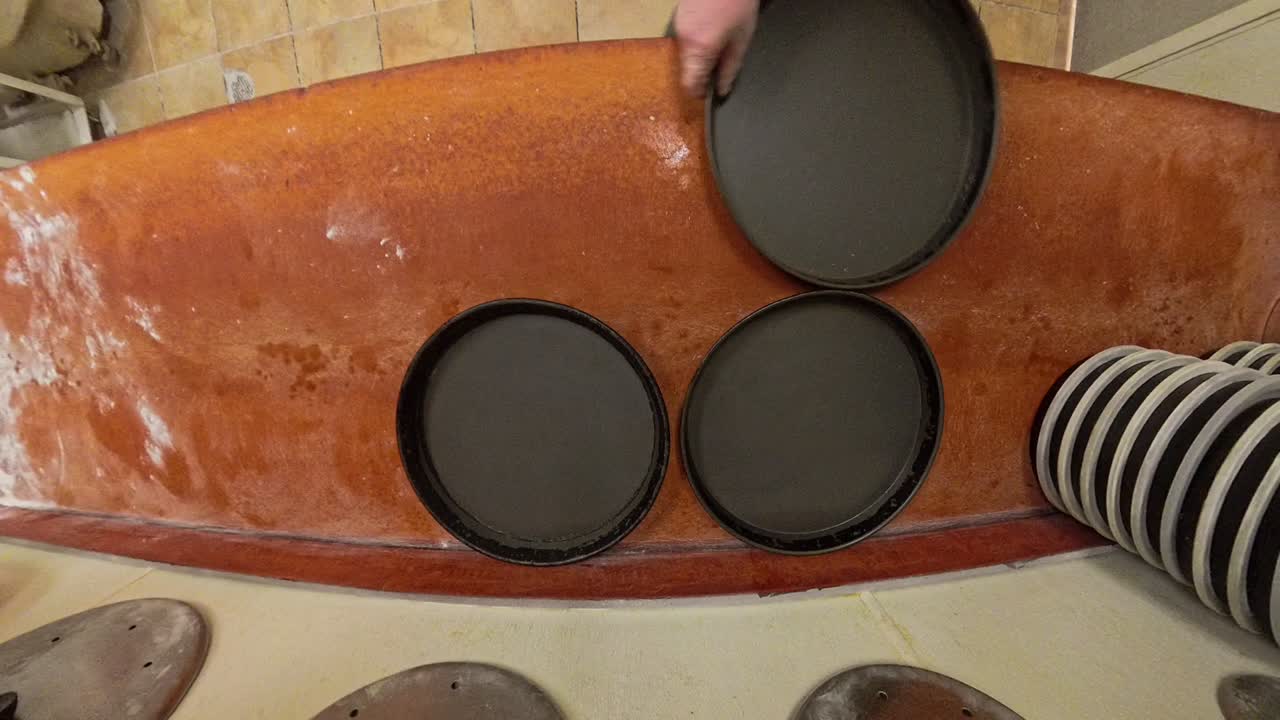 Top Down view deep dish pizza pans being arranged on a table.