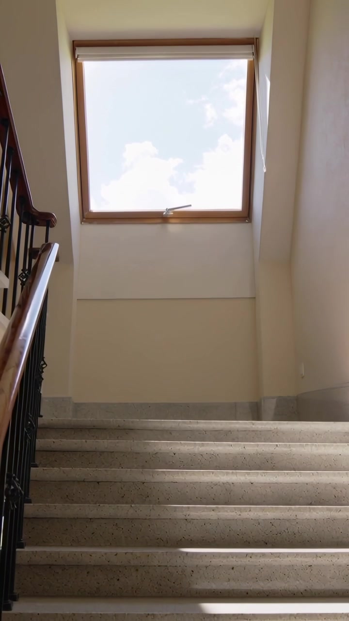 Video verticale: Inclinando la telecamera a mano verso l'alto verso il lucernario per mostrare i gradini, la ringhiera in legno e il sole sul pianerottolo