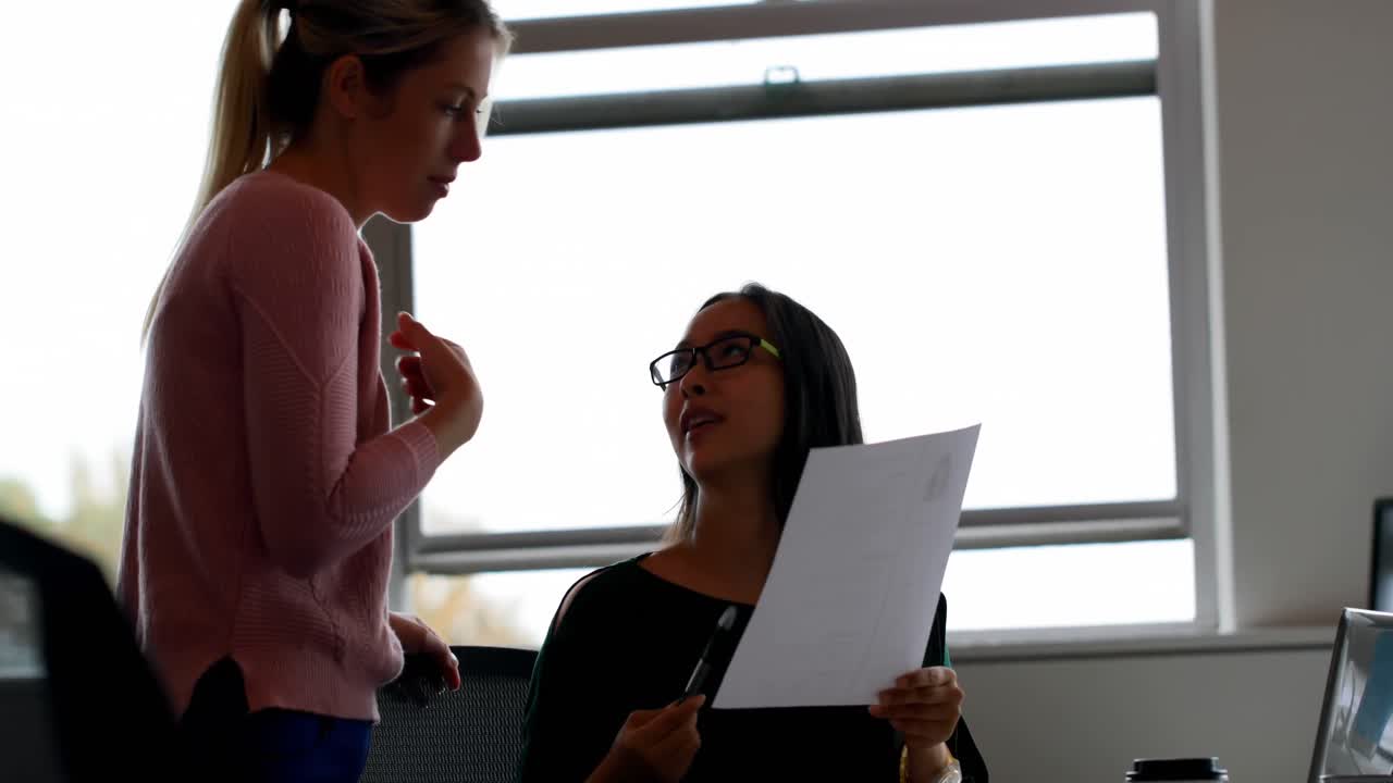 Colegas de trabalho discutindo um documento no escritório 4k