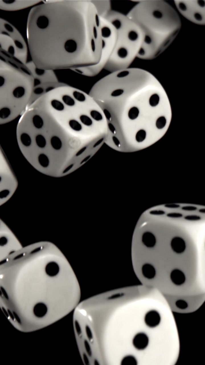 Hvide terninger svæver opad mod en sort baggrund i slowmotion