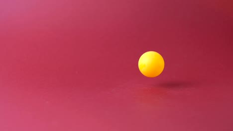 male hand throws a yellow ball on a red background