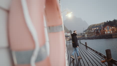 Rainy-evening-in-Reine,-Norwegian-fishing-village,-lone-man-in-misty-port