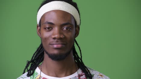 young handsome african man with dreadlocks against green background