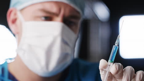 Male-healthcare-worker-flicking-barrel-of-syringe,-close-up