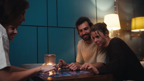 un grupo de amigos felices progresan jugando a un juego de mesa y se dan cinco como signo de victoria en una habitación acogedora por la noche