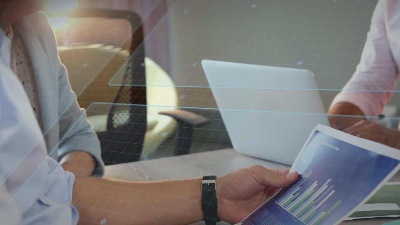 Hand grasping report overlay sparking finance insight as man tracing data, partner checking laptop