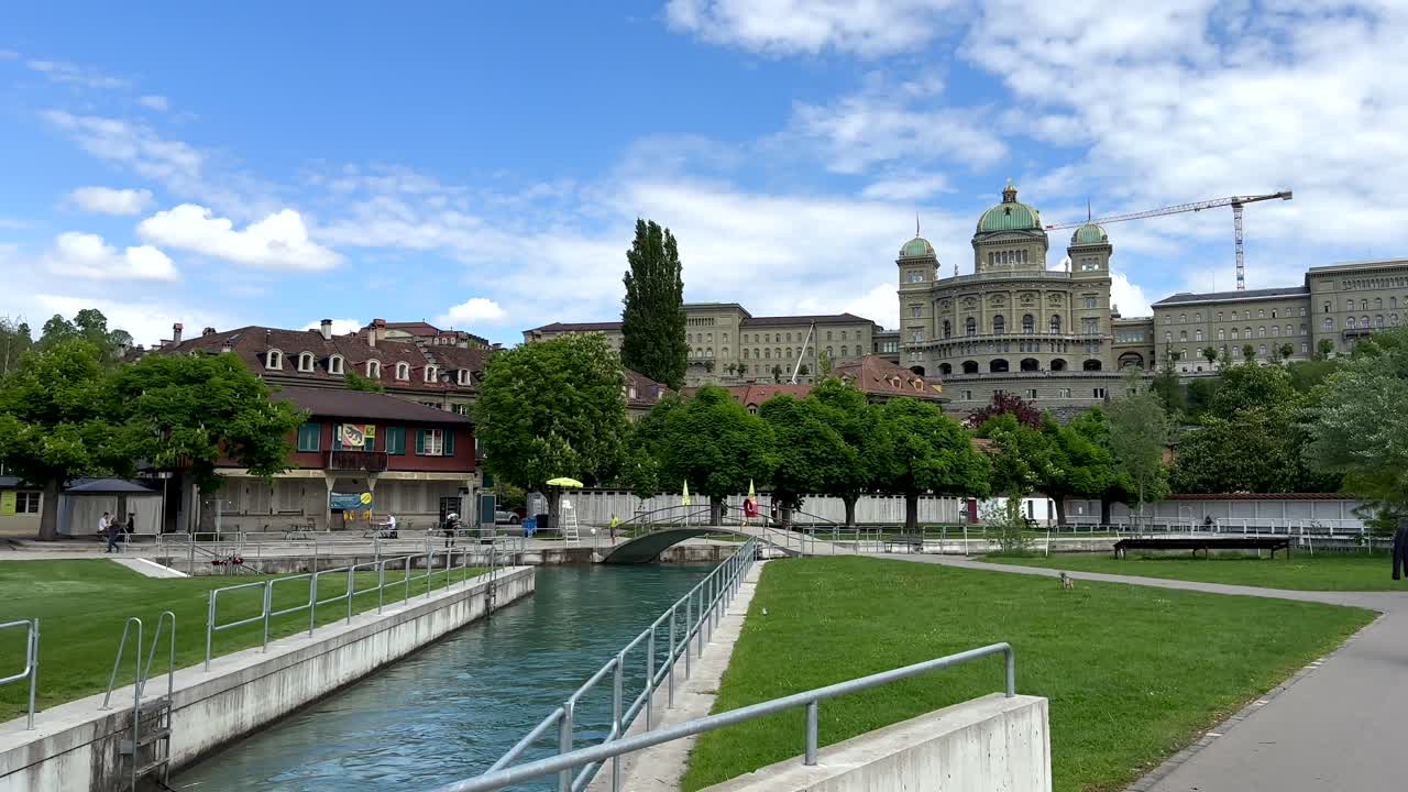 River park with historic Bundeshaus Curia Confoederationis Helveticae Federal Palace. Bern City during sunny day, Switzerland. Wide shot.