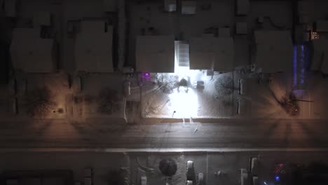 a tractor moves mthodically clearing fresh snow from a suburban driveway at night