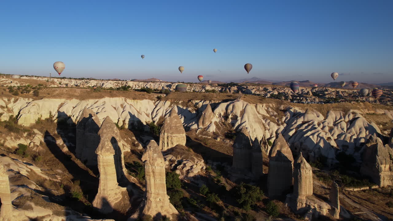 vista aérea de globos aerostáticos y formaciones rocosas de chimenea en cappadocia turquía en la mañana soleada, disparo de drones