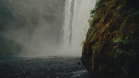 Revela-Una-Toma-Desde-Detrás-De-Los-Acantilados-De-Las-Pintorescas-Y-Brumosas-Cataratas-De-Skógafoss-En-Islandia,-Slomo