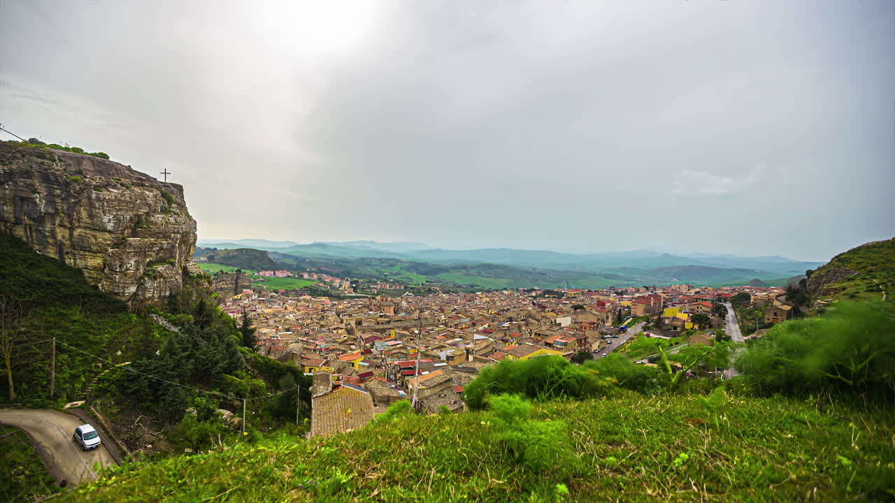 하늘에 빽빽한 구름이 낀 꼴레오네 마을의 키에사 마리아 ss 델 말파소에서 목가적인 전망을 저속 촬영한 사진 - 배경에 있는 산맥의 실루엣