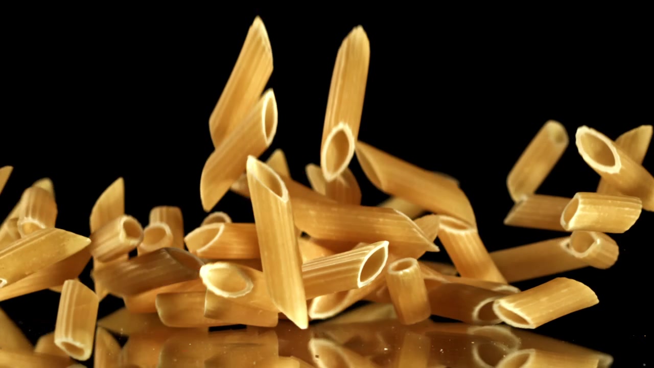 Penne secche che cadono al rallentatore su sfondo nero