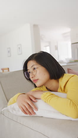vertical video of portrait of happy asian woman lying in living room