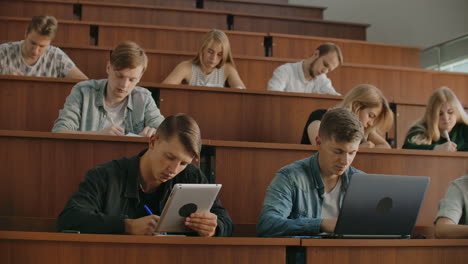 large group of multi ethnic students working on the laptops while listening to a lecture in the modern classroom. bright young people study at university.